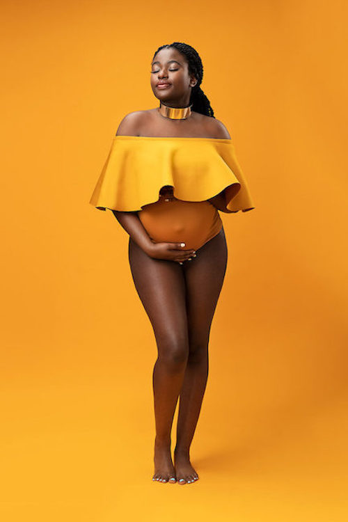 Maternity image of woman against orange background.