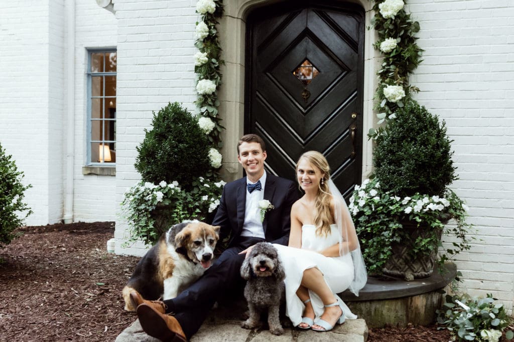Bride, groom and their dogs in front of groom's childhood home turned wedding venue.